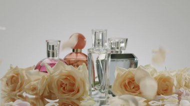 Zarif parfüm şişelerinin yansıtıcı yüzeyde narin gül yapraklarıyla çevrili güzel bir düzenleme. Lüks, parfüm, güzellik ve romantizm temaları için mükemmel..