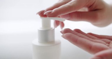 Kadın elleri pompa plastik losyon şişesini itiyor ellerine nemlendirici krem sürüyor. Cilt bakımı, hijyen ve sağlıklı yaşam konsepti. Kapatın. Banyoda yıkanmak, gelişmiş cilt bakımı için yumuşak jel kullanmak..