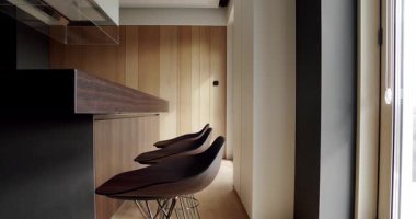 Lüks evde modern iç mekan. Minimalist bir mutfağın içinde. Açık Ahşap Duvar ve Zemin. Modern mutfak ve bardaki kahverengi sandalyeler minimalist dairede. Mutfak odası doğal ahşap.