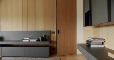 Ahşap duvarlı ve gri mobilyalı minimalist oturma odası. Gri kitaplıklı lüks Modern Ev İçi. Moda mobilyalar. Minimalist İç mimari, modern raflar, kitaplar, ahşap kapılar.