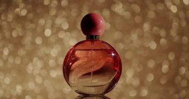 Altın sarısı arka planda sergilenen zarif parfüm şişesi lüks ve sofistike şeyleri yakalıyor. Güzellik ve parfüm markası için ideal. Altın Bokeh Arkaplanlı Parfüm Şişesi
