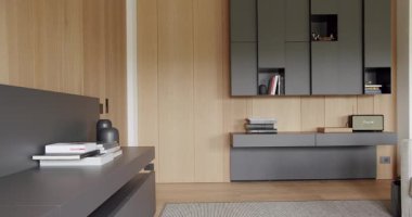 Ahşap duvarlı ve gri mobilyalı modern Minimalist oturma odası. Köşedeki kanepe ve kitaplığı olan lüks modern ev iç mimarisi. Rafları ve kitabı olan rahat Modern Mobilya Tasarımı.