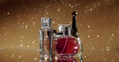 Parlak altın bir arka planda sergilenen zarif parfüm şişeleri koleksiyonu. Görüntü lüksün, güzelliğin ve entelektüelliğin özünü yakalıyor. Güzellik ve moda temaları için mükemmel..