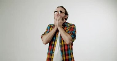 Güneş gözlüklü ve ekose gömlekli şaşırmış bir adam şaşkınlıkla tepki verir. Ağzını kapatıyor ve soluk soluğa kalıyor. Beyaz bir arka plana karşı şok ve inançsızlığını dile getiriyor. Şaşırtmak için mükemmel bir yol.