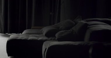 Siyah mobilyaları ve büyük siyah perdeleri olan modern Minimalist oturma odası. Köşedeki kanepe ve kitaplığı olan lüks modern ev iç mimarisi. Moda mobilyalar. Minimalist Ev İçi.