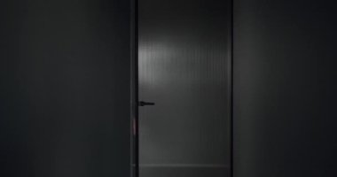 The man opens the transparent door in the modern house. modern interior design with gray colors.