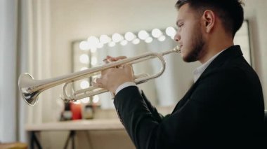 Takım elbiseli genç ve yakışıklı bir adam arzu ve ilhamla trompet çalar. Canlı caz konseri. Müzik tutkusu. Genç trompetçinin yakın eli. Müzik odası.