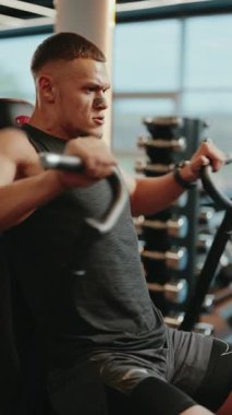 Kararlı bir erkek atlet modern bir spor salonunda göğüs sineği egzersizleri yapıyor. Gücünü ve kas kütlesini arttıran sporcu, düzenli egzersiz ve fitness rejimine odaklanıyor..