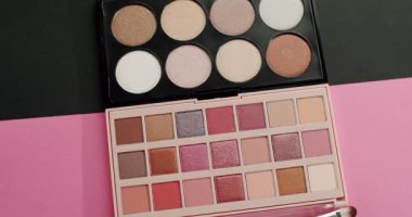 Renkli göz farı ve parlak paletler, parlak pembe ve siyah arka planda görünen profesyonel makyaj fırçaları, güzellik ve kozmetik sanatları için çeşitli gölgeler sergiliyor.