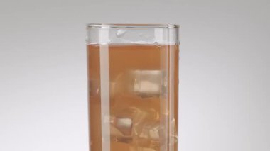 Soğuk, pembe greyfurt suyunun yavaş çekimde bir testiden buz küpleriyle dolu uzun bir bardağa dönüşmesi. Temiz, beyaz arka planda izole edilmiş, susuzluğu gideren mükemmel bir içecek..