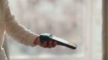 Bir POS terminalinden kredi kartı çekerek güvenli bir ödeme yapan bir kişinin yakın plan görüntüsü, perakende ortamda hızlı ve kolay nakitsiz bir işlem gösteriyor