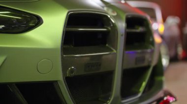 Modern lüks süper arabaların göz kamaştırıcı yakın çekimi ön tampon, mat yeşil bitiş ve agresif karbon fiber hava girişleri, sığ bir alan derinliği ile yavaş çekim