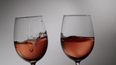 Kutlama için birbirine vurulan pembe şarapla dolu iki zarif kristal kadeh, kutlama kadehi için bir araya gelen gül şarabıyla dolu iki kadehin dramatik yavaş çekim çekimi.