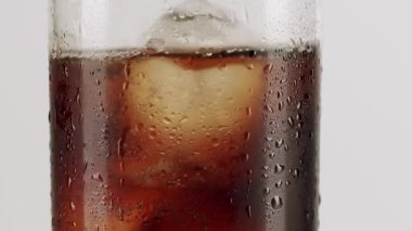 Soğuk kola bardağını köpürten baloncuklar ve buz küpleriyle tazeleyen, beyaz bir zemin üzerinde izole edilmiş, dıştaki yoğunluk damlacıkları serin, susuzluk giderici bir etki yaratıyor.