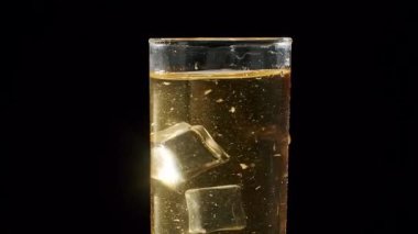 Altın alkolün buzla dolu bir bardağa doldurulduğu yakın plan, köpüren baloncuklar ve ferahlatıcı soğuk bir içecek yaratıyor, ayrıntılı bir yavaş çekim ile kaydediliyor..