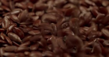 Ağır çekimde dönen kahverengi keten tohumlarının aşırı yakın çekimi, vejetaryen beslenme, beslenme, sağlıklı beslenme ve organik süper yiyeceklerle sağlıklı beslenme tarzı için kullanılan sağlıklı, ham gıda bileşenlerinin detaylı bir görüntüsü.