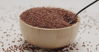 Kırmızı organik kinoa tohumları yavaş çekimde dönüyor, sağlıklı pişmemiş tahılın detaylı doku görüntüsünü sağlıyor. Makro çekim sağlıklı beslenme için süper gıdaların kalitesini vurgular.