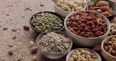 Sağlıklı fındık ve tohumların ahşap bir arka planda, dengeli bir diyet için vitamin ve besin kaynağını temsil eden, çeşitli vejetaryen protein abur cuburları sergiliyor.