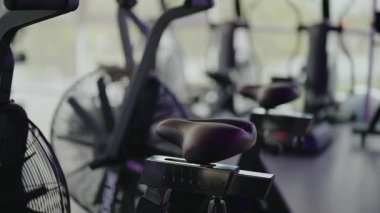 Modern bir spor salonunda koltuk ayarlama mekanizmasına odaklanmış boş egzersiz bisikletlerine yakın çekim. zindelik, sağlık, ya da yaşam tarzı içeriği.