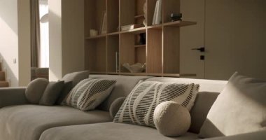 Huzurlu oturma odası rahat gri kanepe ve şık yastıklar sıcak sabah güneşinin tadını çıkarıyor, hareketli gölgeler yaratıyor ve çağdaş bir ev içinde rahat bir atmosfer yaratıyor.