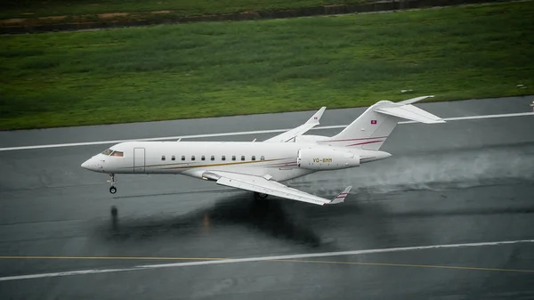 Jet privé Bombardier Global 5000 atterrissant sur piste mouillée à Images De Stock Libres De Droits