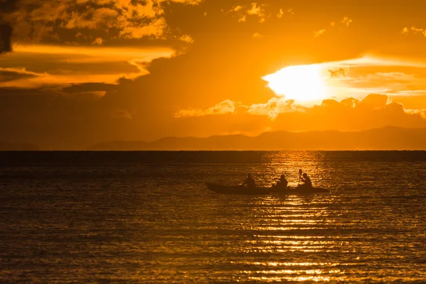 Люди плавают на байдарках в океане на закате — стоковое фото