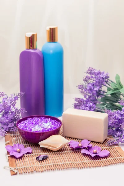 Salle de bains décor intérieur avec du sel de mer, des bouteilles et du savon. Produits et accessoires d'hygiène de couleur lavande et violette . — Photo