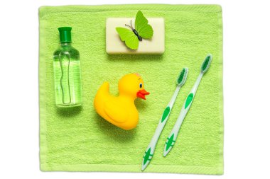 Banyo aksesuarları üzerinde yeşil bir havlu. Plastik ördek, diş fırçası, sabun ve losyon. Bebek bakım aksesuarları Banyo için. Çocuklar için oyuncak sarı ördek yavrusu.