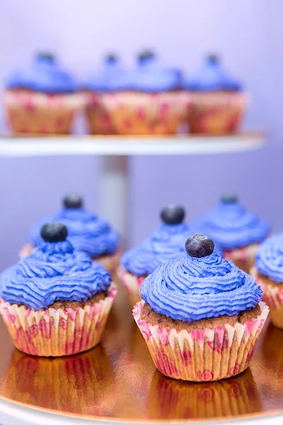 Blueberry muffin op een stand. Party decoratie eten. Cupcakes met bessen en room. Paarse kleur taarten. — Stockfoto