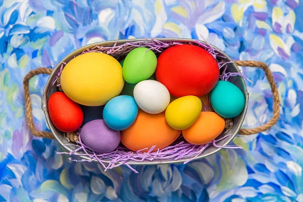 Huevos de Pascua coloridos sobre fondo brillante. Vacaciones de Pascua. Fondo multicolor de color verde, azul y púrpura. Huevos de Pascua en una cesta . — Foto de Stock