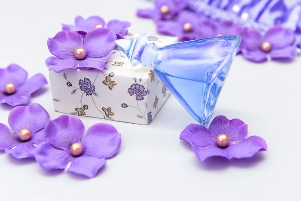 Bouteille de parfum avec quelques décorations violettes et roses sur fond blanc — Photo