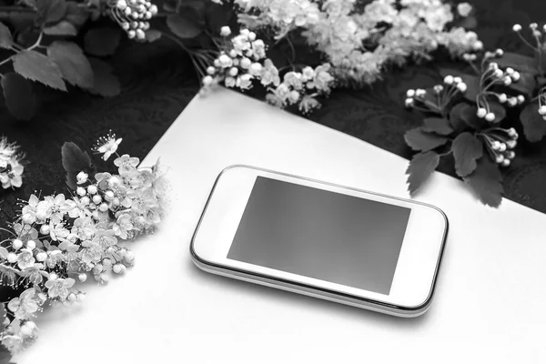 Hermosas ramas florales y un teléfono blanco sobre un fondo de papel texturizado y tela oscura — Foto de Stock
