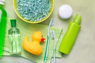 Banyo aksesuarları üzerinde yeşil bir havlu. Plastik ördek, diş fırçası, sabun ve losyon