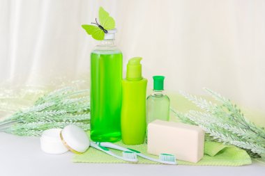 Banyo aksesuarları üzerinde yeşil bir havlu. Diş fırçaları, sabun ve losyon.