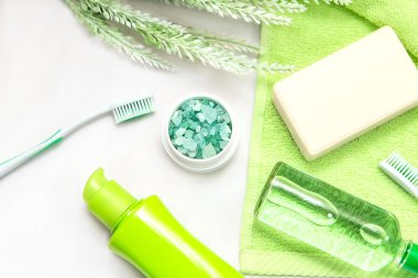 Banyo aksesuarları üzerinde yeşil bir havlu. Diş fırçaları, sabun ve losyon.