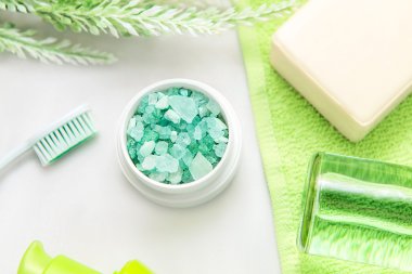 Banyo aksesuarları üzerinde yeşil bir havlu. Diş fırçaları, sabun ve losyon.
