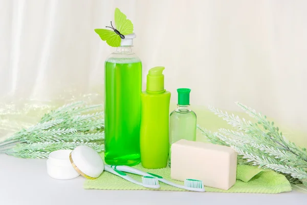 Accesorios de baño en una toalla verde. Cepillos de dientes, jabón y loción . — Foto de Stock