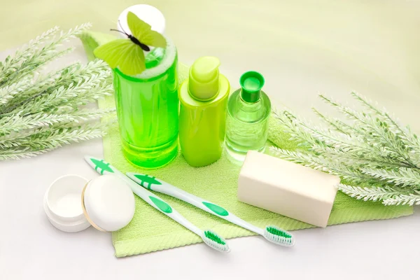 Accessoires de salle de bain sur une serviette verte. Brosses à dents, savon et lotion . — Photo