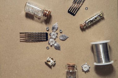 Create handmade jewelry. Accessories for manufacturing costume jewelry. Combs, glass beads, metal elements, wire, crystals, pendants on a beige background