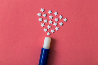 Yıldızlı dudaklar için beyaz hijyenik ruj pembe bir kağıtta bulunur. Yakından çekilmiş..