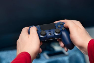 Adamın elleri konsol kumandasını ön planda tutuyor. Evde video oyunu oynuyorum. Modern zamanlardaki hobiler.