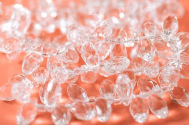 Şeftali arkaplanına, yüzü kesilmiş damlalar şeklinde kristal boncuklar yerleştirilir. El yapımı mücevherler için şeffaf boncuklar.