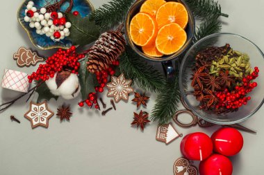 Masada Noel eşyaları var. Bir fincanda mandallar, köknar dalları, bir koni, kış baharatları, zencefilli kurabiyeler, kutsal meyveler, kırmızı mumlar ve daha fazlası.