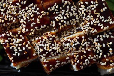 Plastik bir tabakta tatlı susam soslu taze pilav ve yılan balığı ruloları. Teslimat servisinden Çin yemeği.