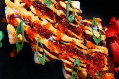 Asya pilavı ve acı soslu taze balık dürümleri dilimlenmiş soğan ve kırmızı balık yumurtası ile süslenmiş.