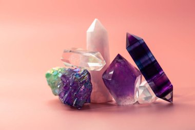 İyileştirme ve büyülü uygulamalar için çeşitli kristaller. Bir sürü güzel yarı değerli taş. Ametist, gül kuvars, florit, pastel pembe arka planda kaya kristali.