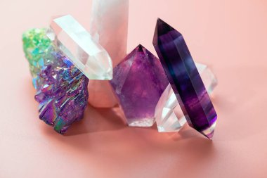 İyileştirme ve büyülü uygulamalar için çeşitli kristaller. Yüzleşik ametist, gül kuvars, florit, kaya kristali, pastel pembe arka planda bir kuvars kümesi.