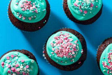 Turkuaz kremalı ve pembe kalp ve yıldız şeklinde şeker serpiştirilmiş kekler. Doğum günü için şeker, Sevgililer Günü, çocuk tatili, Paskalya. Üst görünüm