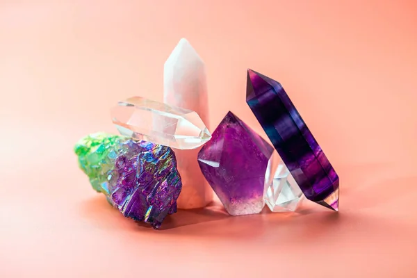 Amethyst, quartz crystals, rose quartz, fluorite of various shapes and colors. Natural semi-precious stones on a pink background