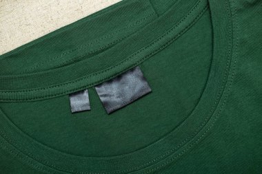 Etiketli standart kesim bir tişörtün detayları. Beyaz arka planda günlük giysiler.